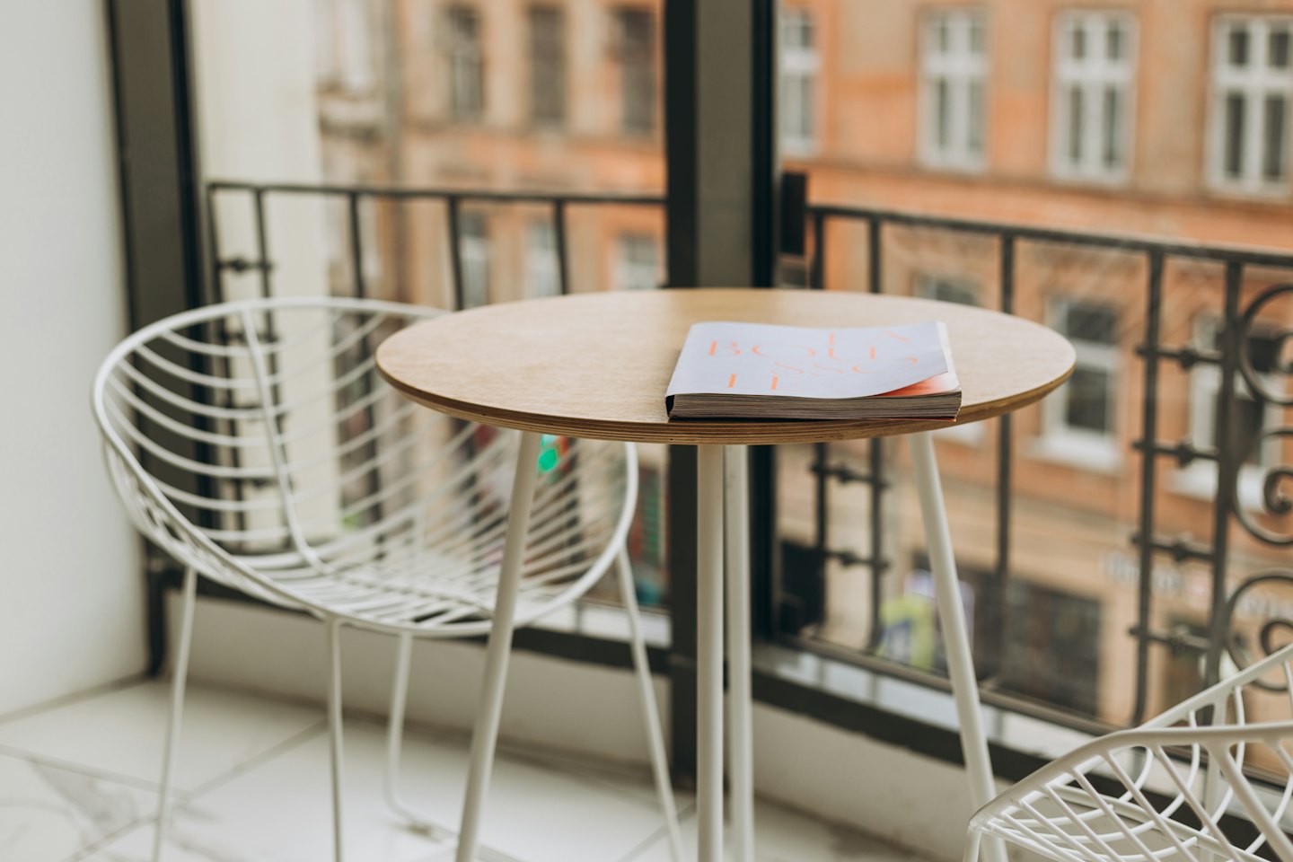 A magazine rests on a wooden table beside a wire chair.